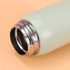Detail view of the stainless steel screw thread and vacuum inner wall of a light green flask