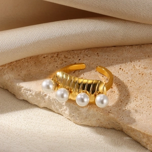 Detail view of gold pearl ring with horizontal textures on a stone and silk background