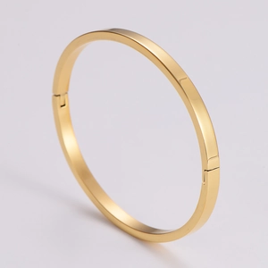 Detail of a polished gold minimalist bangle with a sleek metallic finish and secure clasp