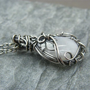 Detailed macro view of moonstone pendant with wire-wrapped silver leaf craftsmanship