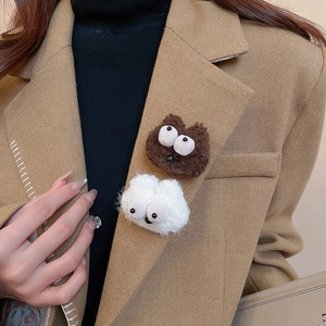 Macro detail of cute fuzzy brooches with big eyes pinned on a beige wool suit jacket