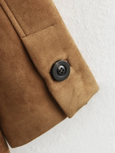 Gros plan du poignet d'une veste en daim marron avec bouton noir et détails de couture