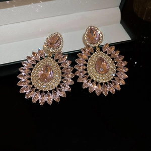 Detailed close-up of pink teardrop crystal flower earrings on a luxury black surface