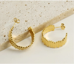 Macro shot of 18K gold plated C-shaped earrings with ribbed texture on stone base