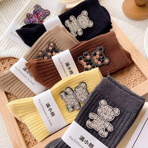 Set of six colorful ribbed crew socks featuring cute rhinestone bear patches on a tray
