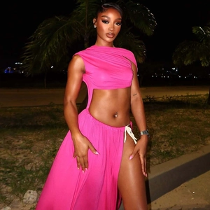 Hot pink cutout maxi dress with high slit and waist tie detail in a tropical night setting