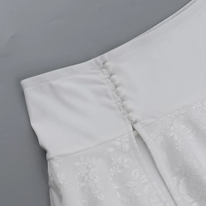 Detailed view of white lace fabric and fabric-covered buttons on a summer crop top
