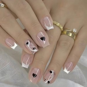 Detail of square nude pink press-on nails with silver glitter lines and heart patterns