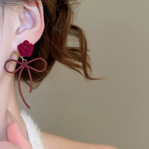 Detailed close-up of velvet rose and dark red bow pendant earrings for women