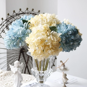 Detail of vintage oil-painted blue and yellow hydrangea artificial flowers in glass vase