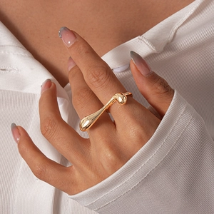 Detail of a minimalist gold irregular geometric ring on a finger with a shiny mirror finish