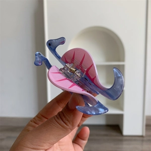 Close-up of a blue dinosaur acrylic hair claw clip with pink dorsal fins detail
