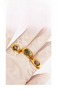 Detail of gold-plated rings set featuring pink heart, star, and smiley face gems