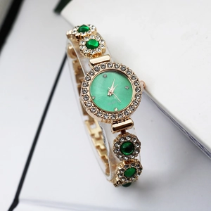 Luxury gold women's watch with green quartz dial and sparkling emerald crystal bracelet