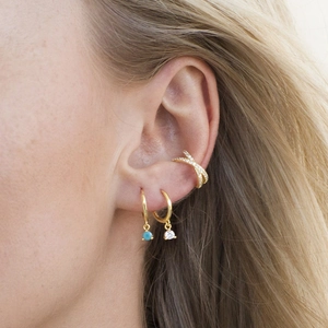 Close-up of gold ear cuff and hoop earrings with turquoise beads and zircons