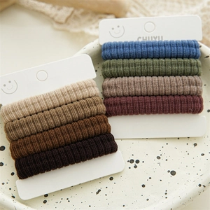 Set of 10 seamless soft fabric hair ties in earthy and deep tones on a ceramic plate