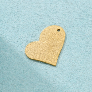 Close-up of golden frosted heart pendant with sparkly finish and single hanging hole