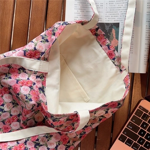 Detail view of pink rose canvas tote bag with interior pocket on a wooden desk