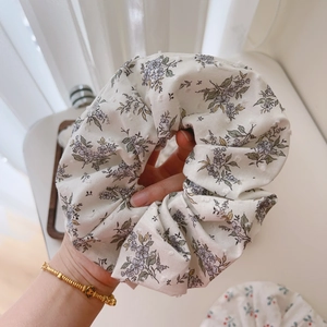 Detailed macro view of cream floral scrunchie with purple patterns and 3D dot embroidery