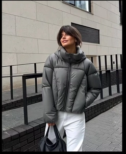 Detail of a dark grey padded puffer jacket with hood and high-quality zipper closure