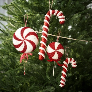 Red and white glitter candy ornaments and candy canes hanging on a green Christmas tree