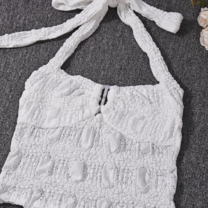Detail of white halter neck crop top showing textured lace fabric and tie-up design