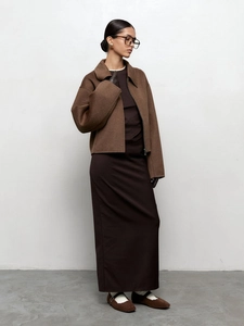 Détail de la veste en laine marron et de la robe mi-longue foncée sur un modèle