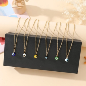 Close-up of seven colorful evil eye beaded necklaces on gold chains in a display box