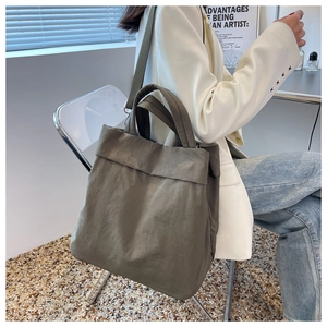 Deep olive nylon tote bag worn by a model in a casual lifestyle setting for daily use
