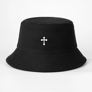 Detail view of a black sun hat featuring a white cross embroidery on cotton fabric