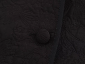 Macro detail of high-quality black floral jacquard fabric and matching fabric button