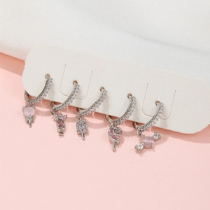 Detail of five silver earrings featuring pink zirconia candy and heart charms