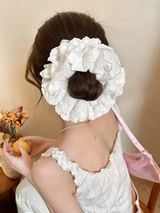 Detailed macro view of white floral lace embroidery and ruffles on an oversized scrunchie
