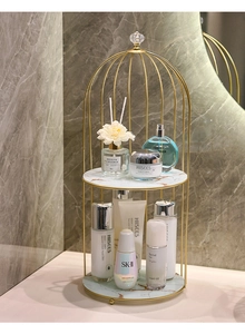 Detail of a birdcage-style golden makeup organizer with white marble textured trays