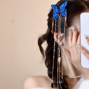 Détail d'une pince à cheveux papillon brodée bleue avec de longues franges en métal doré