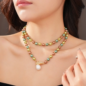 Dettaglio macro di una collana di perle a due strati con perle verdi e pendente a foglia