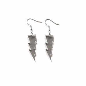 Macro detail of grey glitter acrylic lightning bolt earrings with metallic hooks