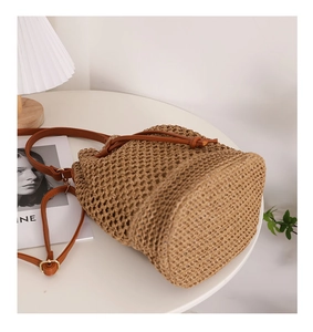 Detail of straw bucket bag with brown leather strap and intricate crochet weaving
