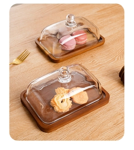 Macro view of rectangular acacia wood butter dishes with clear glass lids on wooden table