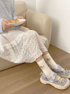 Detail of white cotton socks featuring cute puppy cake embroidery and cake lettering
