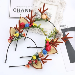 Detail of Christmas reindeer antler headband with festive pine cones and colorful berries