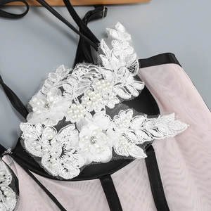 Detail of pink mesh dress featuring white floral lace with pearls and rhinestones