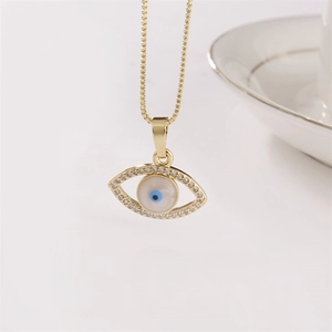 Halskette mit Evil Eye Anhänger in Gold mit blauen und weißen Kristallen auf weißem Grund