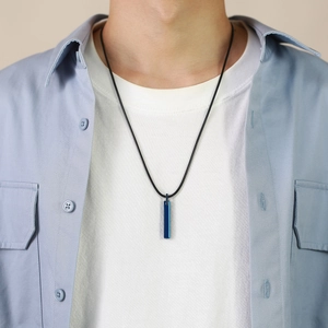 Detail view of a men's necklace with a polished blue rectangular pendant on a black cord