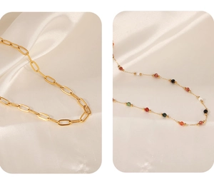 Close-up of golden paperclip link chain and colorful beaded necklace on white silk fabric