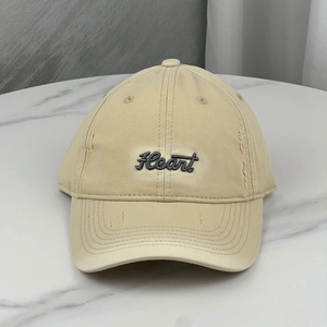 Detailed macro view of beige cotton baseball cap with Heart embroidery and distressed holes