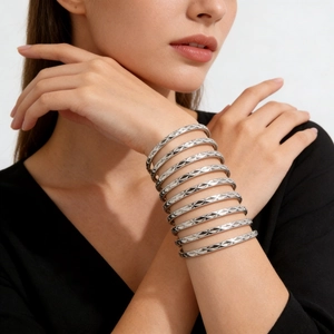 Close-up of stacked silver titanium steel bangles with diamond-cut geometric textures
