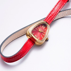 Detailed macro of the gold snake-head watch case with crystal bezel and red dial