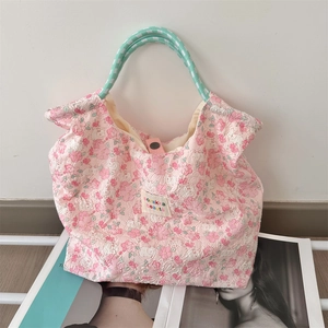 Dettaglio borsa a fiori rosa con trama a rilievo 3D e manici intrecciati verdi