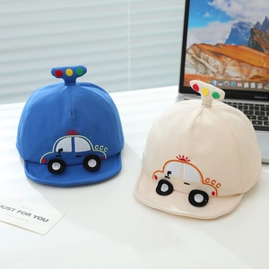 Détail de casquettes bébé avec broderie voiture et pompons décoratifs sur le dessus